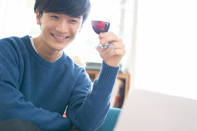 自宅でワインを飲む男性