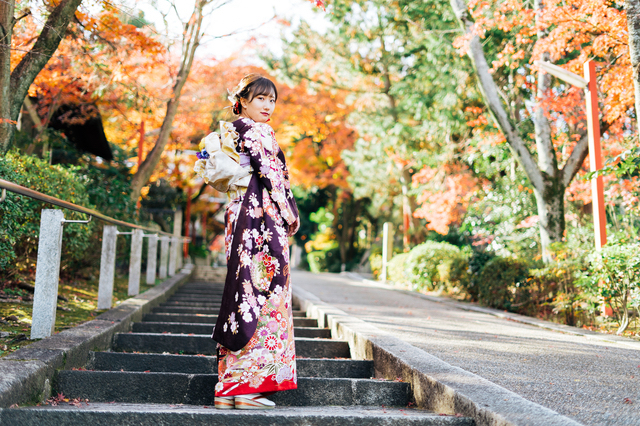 紅葉の時期に神社に祈願する女子大生