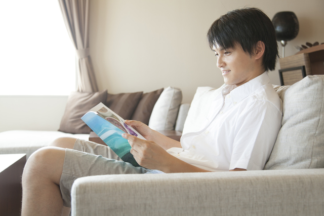 部屋で雑誌を読む男性